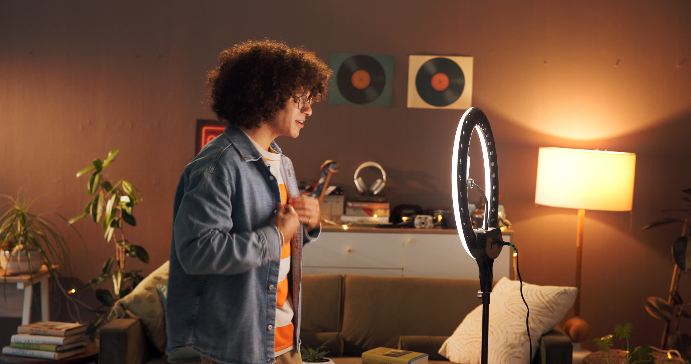 A man filming himself with a ring light at home in the evening